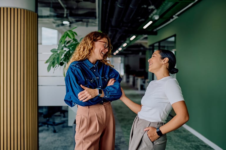 Two professional women colleagues in modern office hallway